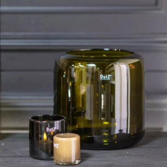 Lowlands Design green glass vase with two small black and beige candle holders on a wooden surface