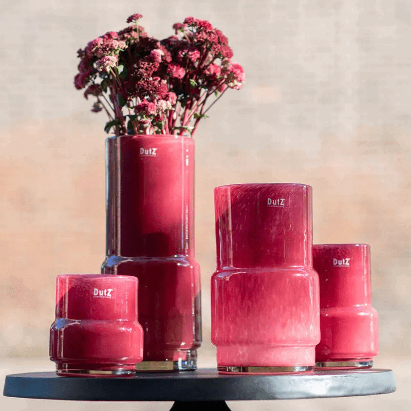 Set of four red glossy design vases from Lowlands Design displayed on a round black table