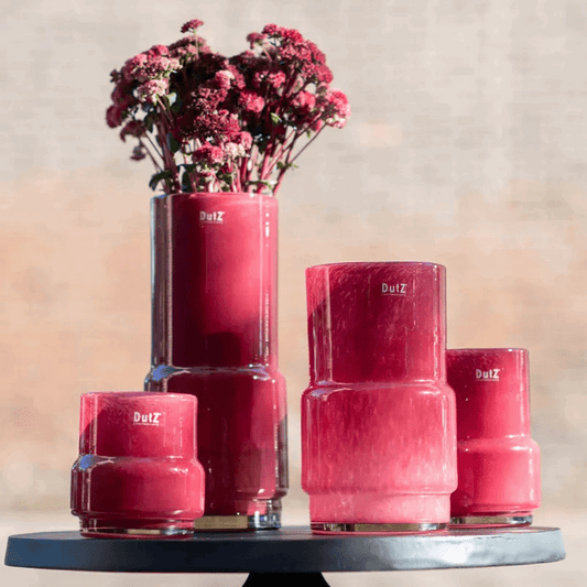 Set of four red glossy design vases from Lowlands Design displayed on a round black table