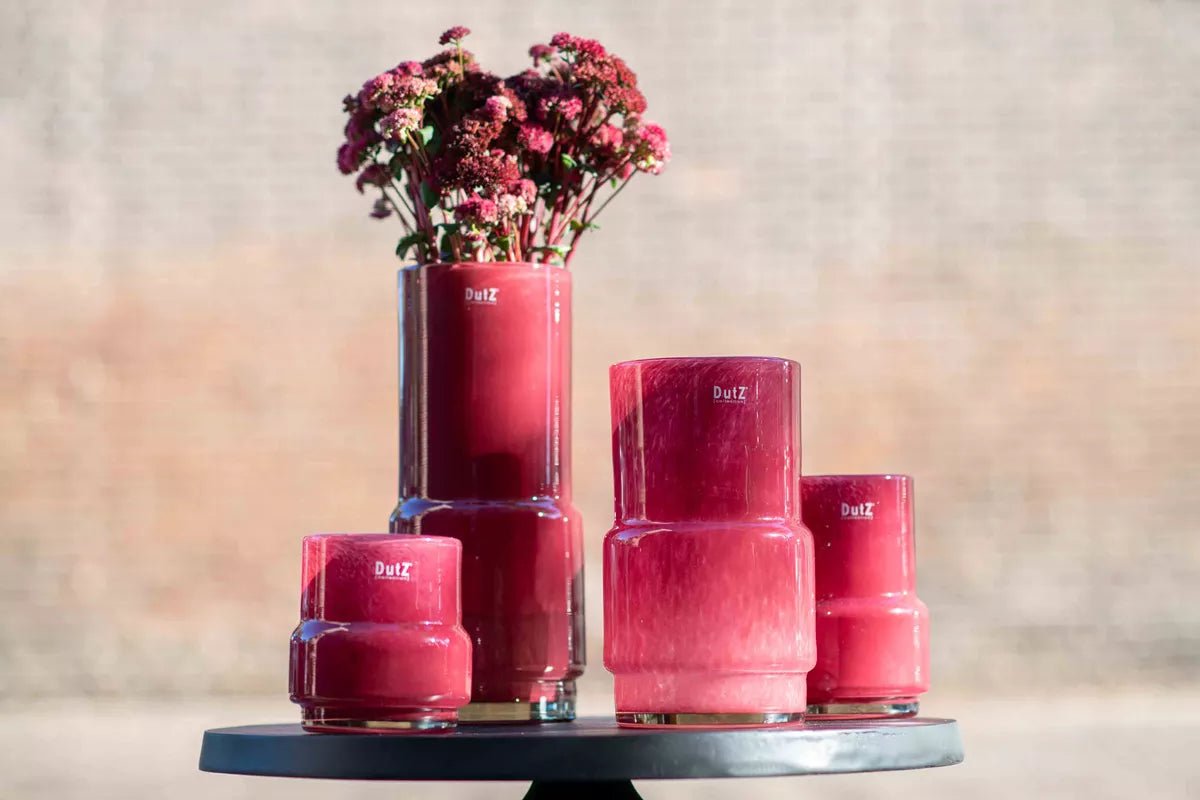 Set of four red Lowlands Design vases in different sizes with flowers in one vase