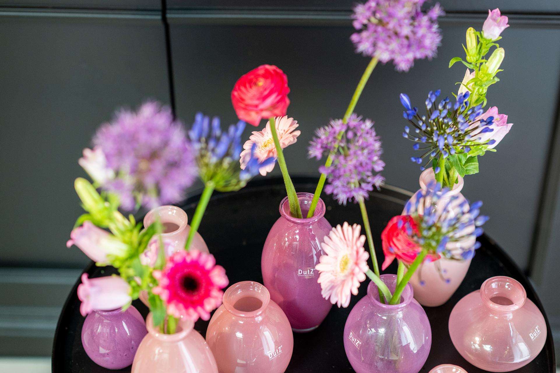 Lowlands Design pink and purple ceramic vase set with assorted colorful flowers on black surface