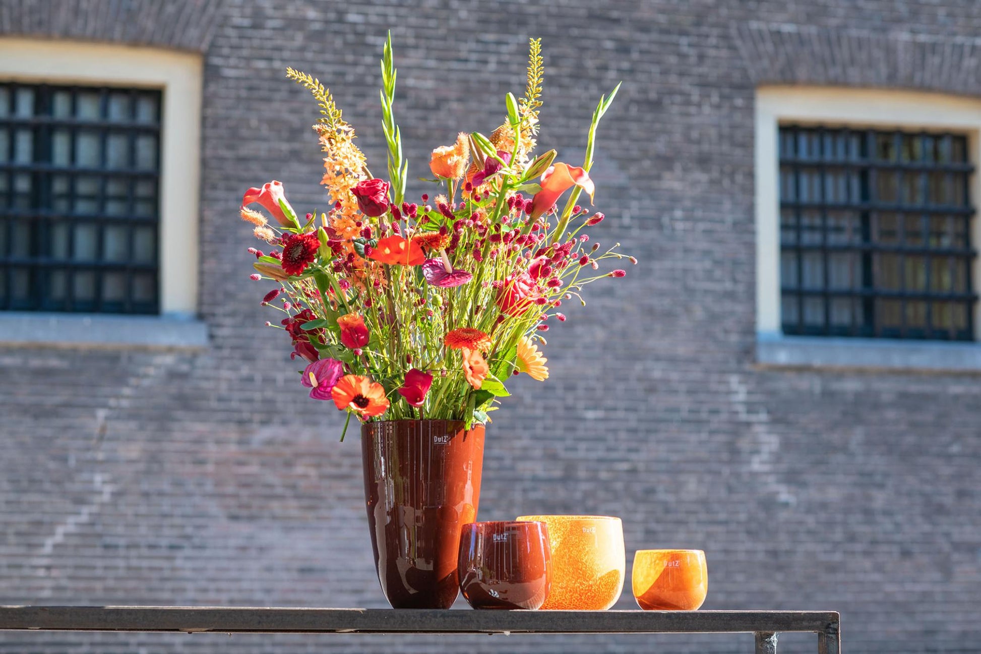 Lowlands Design flowervase glass filled with vibrant floral arrangement and decorative candles