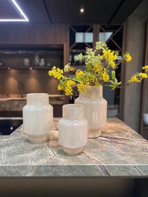 Set of three elegant Lowlands Design glass flower vases on a marble countertop with fresh yellow flowers