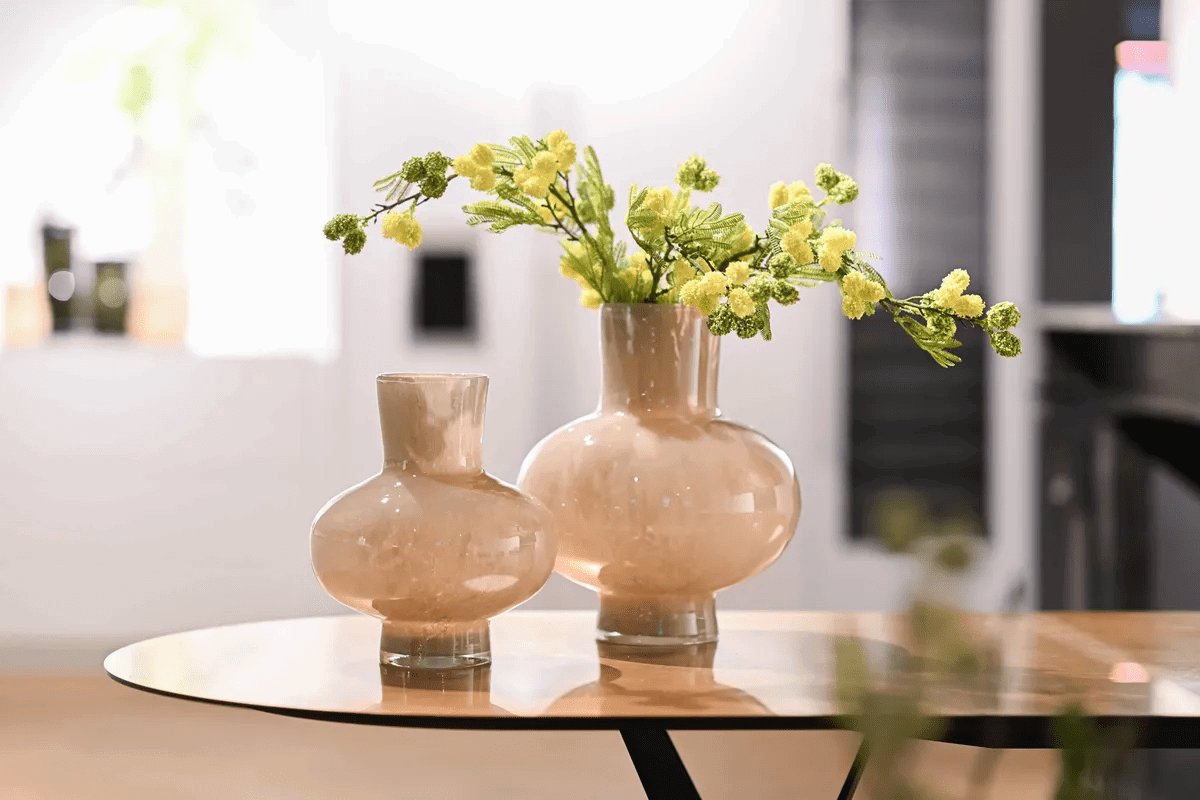 Lowlands Design beige glass vase set with bulbous shapes on a round table with yellow flowers